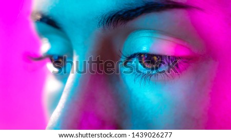 Girl portrait close up posing with light of neon lamps and smoke over futuristic pink and blue neon background.  