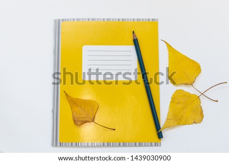 Back to school and education minimalist concept with school notebook, pencil and yellow autumn leaves. New academic year and autumn concept.