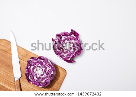 top view of red cabbage on wooden chopping board and knife on white background