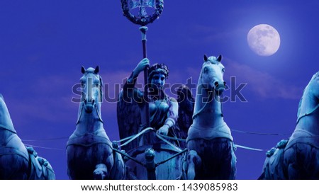 Brandenburg Gate at night in the moonlight,against the backdrop of a large white moon. Statue of the Goddess Victoria on Epic Brandenburg Tor(Gate) with the German banner(symbol).Closeup.Great picture