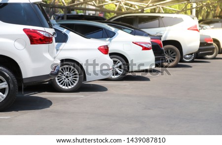 Closeup of rear, back side of white car with  other cars parking in parking lot with natural background in bright sunny day. The mean of simply transportation in modern world.
