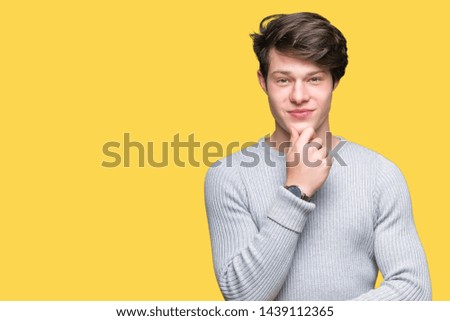 Young handsome man wearing winter sweater over isolated background looking confident at the camera with smile with crossed arms and hand raised on chin. Thinking positive.