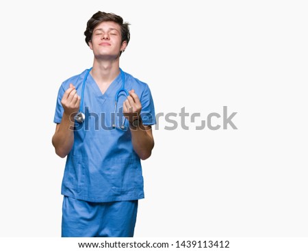 Young doctor wearing medical uniform over isolated background Doing money gesture with hand, asking for salary payment, millionaire business