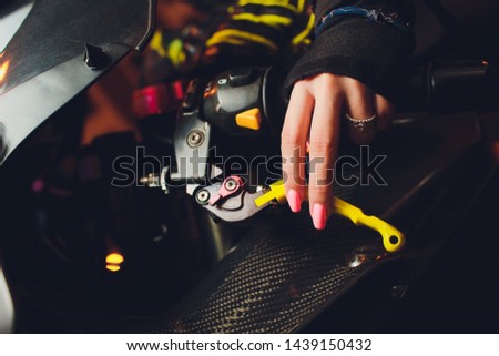 Woman's hand holding steering wheel motorcycle yellow manicure.
