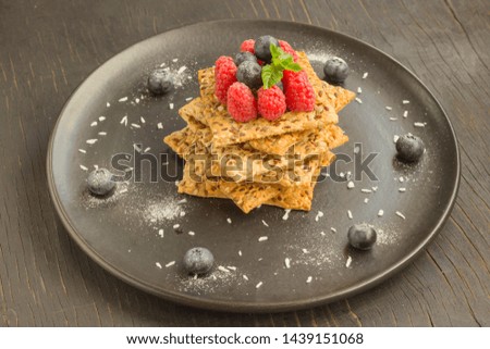 Biscuits with whole grains. Raspberry and blueberry berries on top. Black plate, top view
