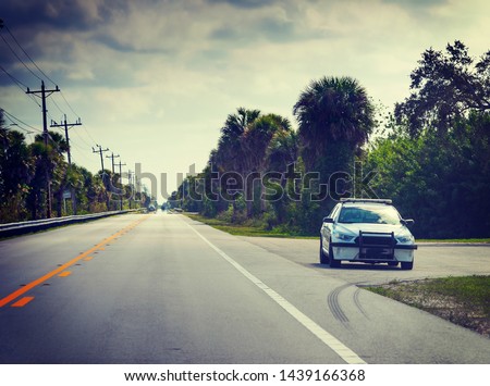 Sheriff car in Florida Everglades parked on the edge of the road on a cloudy day, USA Royalty-Free Stock Photo #1439166368