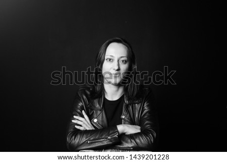 Studio portrait of an attractive young woman in a black leather jacket against a plain background