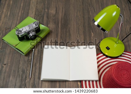 Green lamp, notepad and camera on wooden background