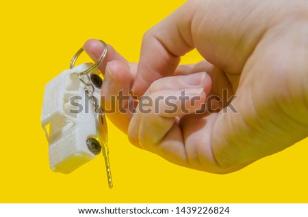 man hand holding a stick figure of a car with keys on a yellow background