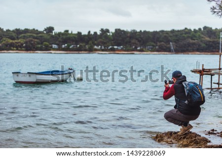 man taking photo of the boat in sea bay stormy weather. travel concept