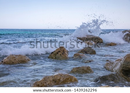 Sea and waves. The sea is a beautiful turquoise sea and white waves beat against the stones on the shore.