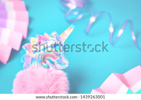 Shiny zine type gradient holographic iridescent head of pink soft fluffy toy unicorn on bright blue background. Celebration or birthday greeting card concept with copy space