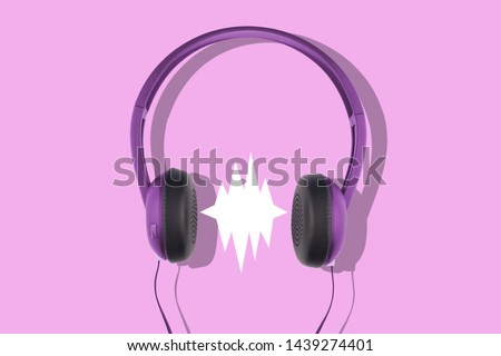 front view closeup of black and violet headphones isolated on pink background with empty comic sound speech bubble 