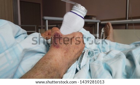 Elderly woman lying on the bed and drinking energy drink.