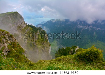 Beautiful view from Niederhorn to huge canyon covered with fog and green forest with Lake Thun (Thunersee) on background in Swiss Alps, Switzerland