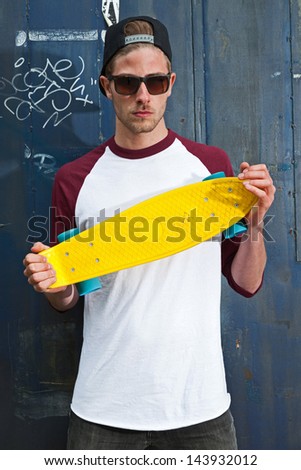 Urban fashion skateboarder with black cap and sunglasses in front of iron wall.