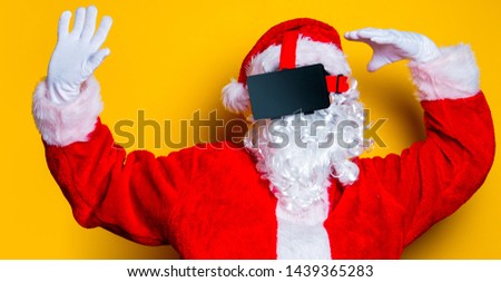 Funny Santa Claus have a joy with VR glasses on yellow background