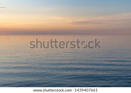 A beautiful sunset over Lake Ontario reflects gold and blue colors into the waves. The Toronto skyline is visible in the distance.