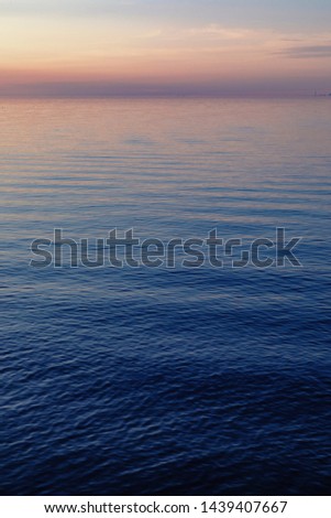 A beautiful sunset over Lake Ontario reflects gold and blue colors into the waves.