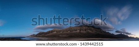 panoramic night photography of a coastal area with beach and cliffs