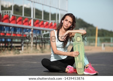 Teenager girl holding skateboard in hands on the cityscape background. Riding on scateboard. Summer concept of extreme sport. Close up portrait.