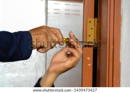 Door repairman, rotating screw, Phillips screwdriver, abstract blur picture