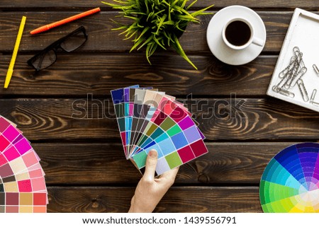 Work space of designer with instruments, pallet in hands, pencils, glasses and coffee wooden background top view