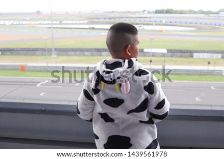 back side of boy in cow mascot cloth standing at stadium.