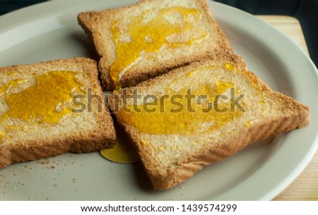 Crunchy toast with natural honey on top on a plate, low key ligt photography and macro photography