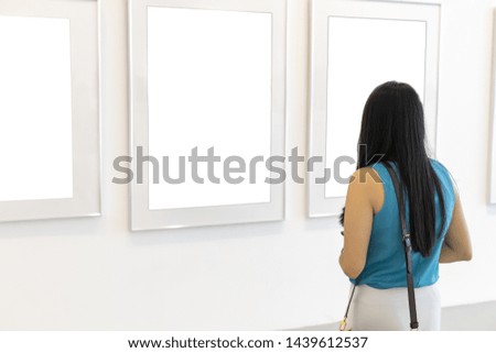 woman looking at white blank canvas on the wall in art gallery with copy space for text or design