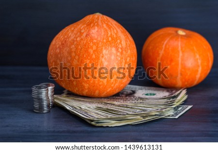 Ripened pumpkin and a bundle of money on a wooden background.