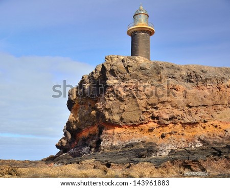 Lighthouse tower near to the cliff on clear blue sky, tip of Jandia, coast of fuerteventura, Canary islands, Spain