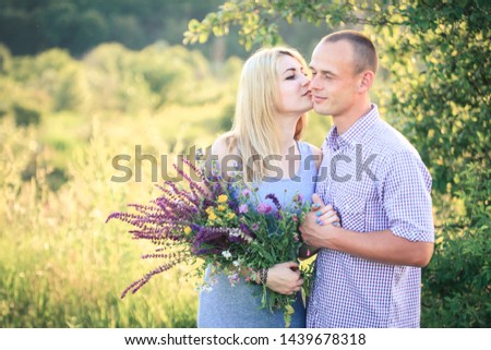Man and woman on nature with a bouquet of flowers. Couple in love. Summer day.
