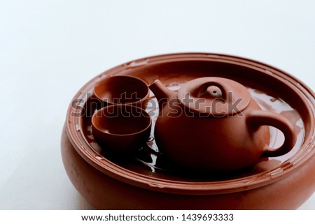 Close up red brown ceramic clay fired teapot and teacups on white background. Traditional Chinese tea culture concept
