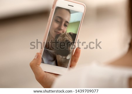 Teenage girl taking selfie with cute pug dog at home, closeup