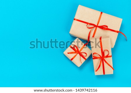 beautiful gift boxes wrapped in paper with a red ribbon and a bow on a blue surface. Top view