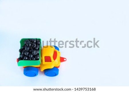 raspberry natural vitamins are in the back of a truck in a children's toy car food delivery truck logistics on white isolated background