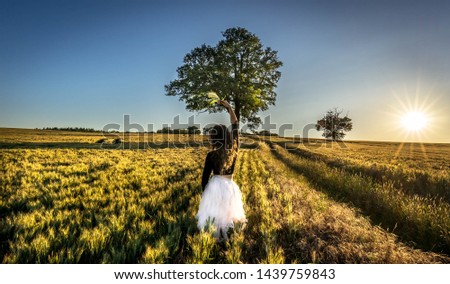 Portrait of a beautiful young woman in white skirt on meadow watching the sunset, enjoying nature