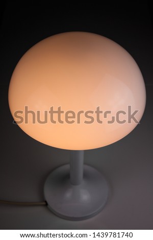 modern desk lamp with mushroom shape spaceage 
vintage midcentury design front side view white black background with warm orange light isolated in the studio HIGH RESOLUTION