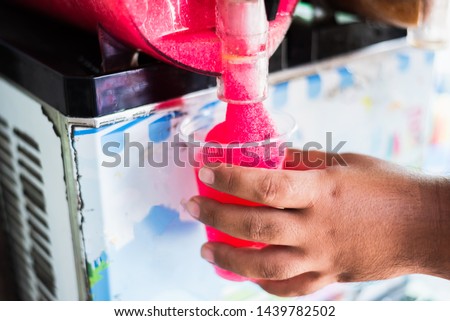 Human hand serving slushy drink from slushy  machine Royalty-Free Stock Photo #1439782502