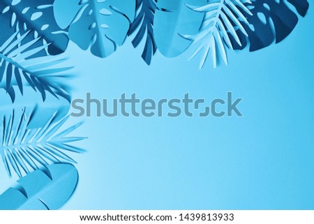 frame of blue minimalistic paper cut palm leaves on blue background with copy space