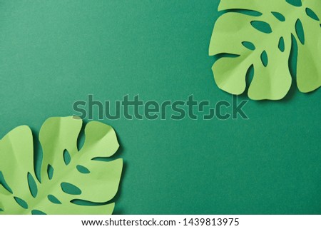 top view of exotic paper cut palm leaves on green background with copy space