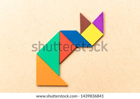 Color tangram puzzle in sitting cat shape on wood background