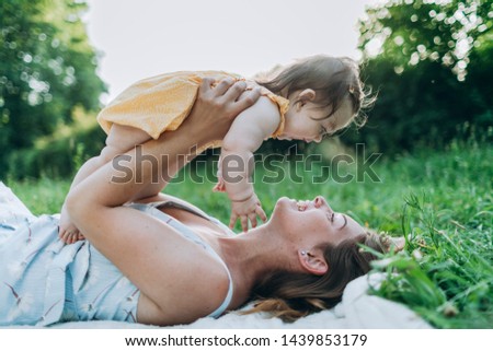 The young mother holds on and plays with his little daughter and kissing