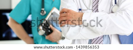 Male doctor with arms crossed on chest standing in line with colleagues in office closeup
