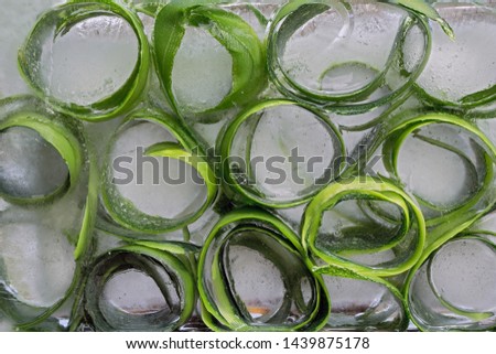 Background  skin and piece of  fresh szucchini   in ice   cube with air bubbles