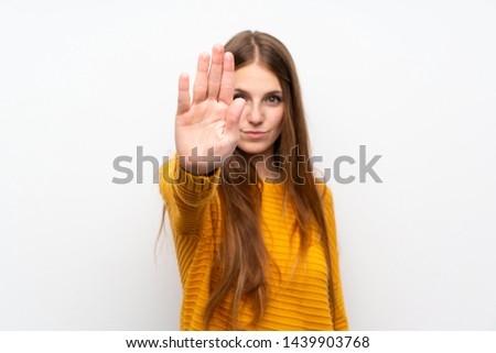 Young woman with yellow over isolated white wall making stop gesture with her hand