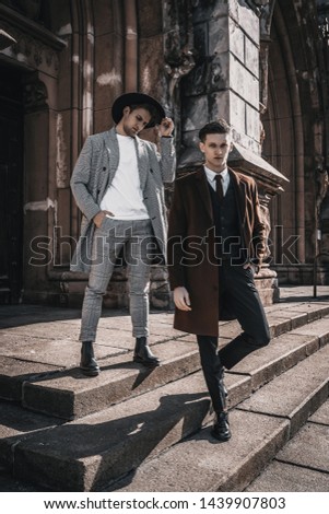 Two fashion men on urban background in stylish casual and classic clothes with trendy hairstyle. Handsome bearded man model portrait on city street Royalty-Free Stock Photo #1439907803