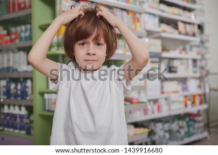 Little boy scratching his head, having lice, copy space. Little schoolboy with lice in his hair, scratching head at drugstore. Child suffering from dandruff