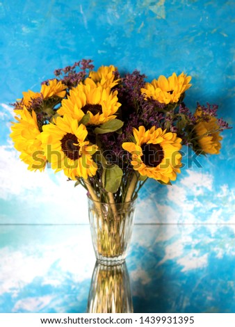 Bouquet of sunflowers in a vase on a mirror table.